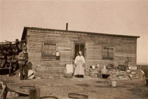 An African American homestead couple stand in front of their home. 