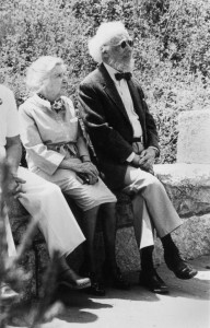 Belle (in a dress) and Norman Winestine (wearing a suit coat and bowtie) sit on a wall listening to speakers at the "Failure is Impossible" celebration in Helena, Montana, to promote passage of the Equal Rights Amendment, July 1, 1982.