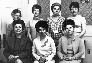 A group portrait of seven women, four standing behind three who are seated.