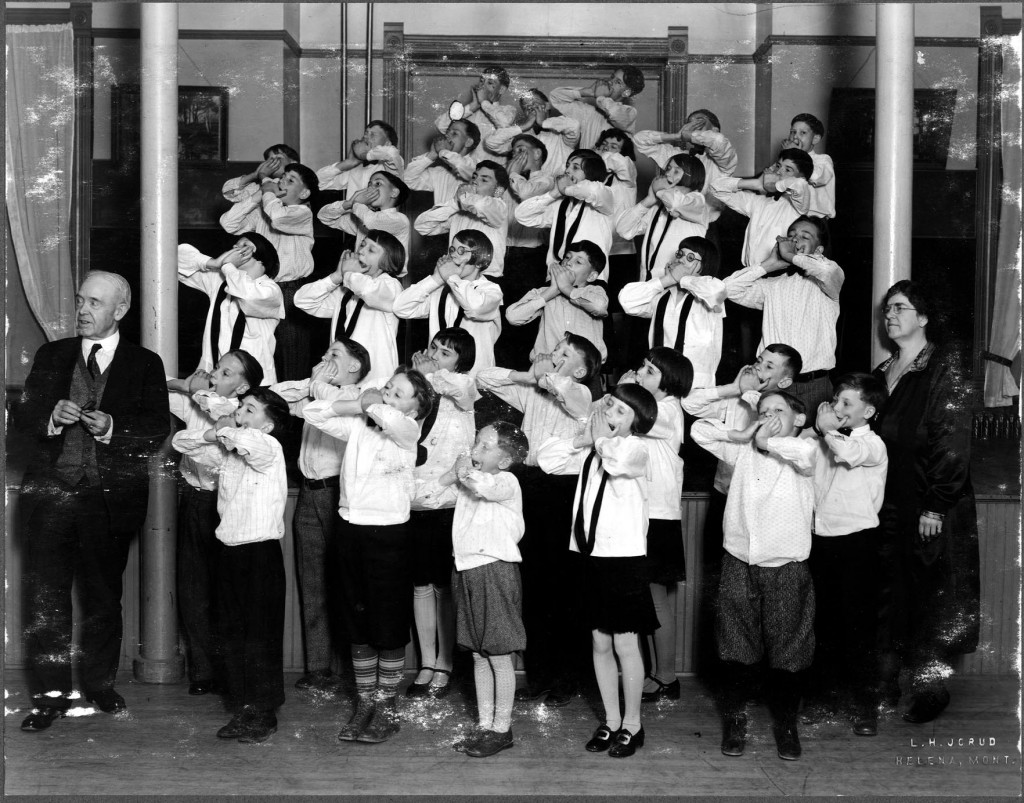 A children's harmonica band, posed with their teacher, Helen Piper, and director A. I Reeves.