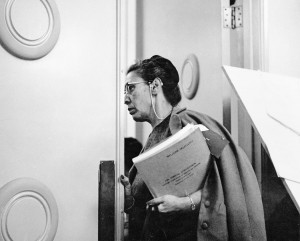 Freda Beazley strides into a meeting holding a folder titled "Welcome Delegates. 15th Annual Convention, National Congress of American Indians.