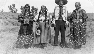 Ellen Bigsam, Mary Ann Coombs, Victor Vanderburg, and Sophie Moise posed outside. Women in long dresses and braids, man in beaded vest and cowboy hat.