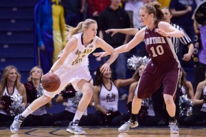 Two women college basketball players vie for the ball at a 2013 NCAA game.